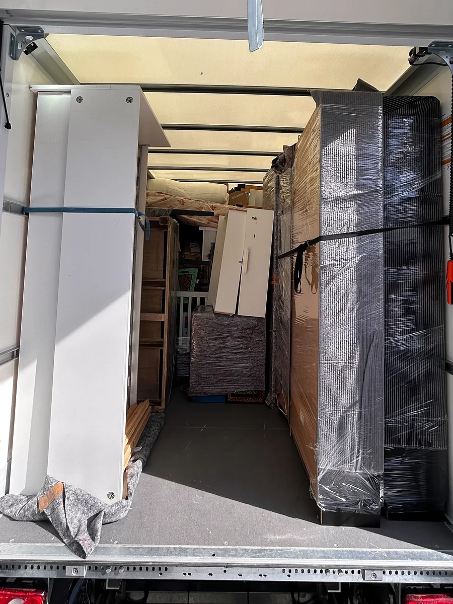 Platzsparend beladener Umzugswagen mit verpackten Schränken, mit Gurten gesichert