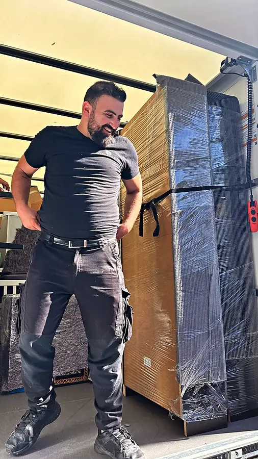 Lächelnder Two-Spears-Mitarbeiter neben einem sicher verpackten Schrank