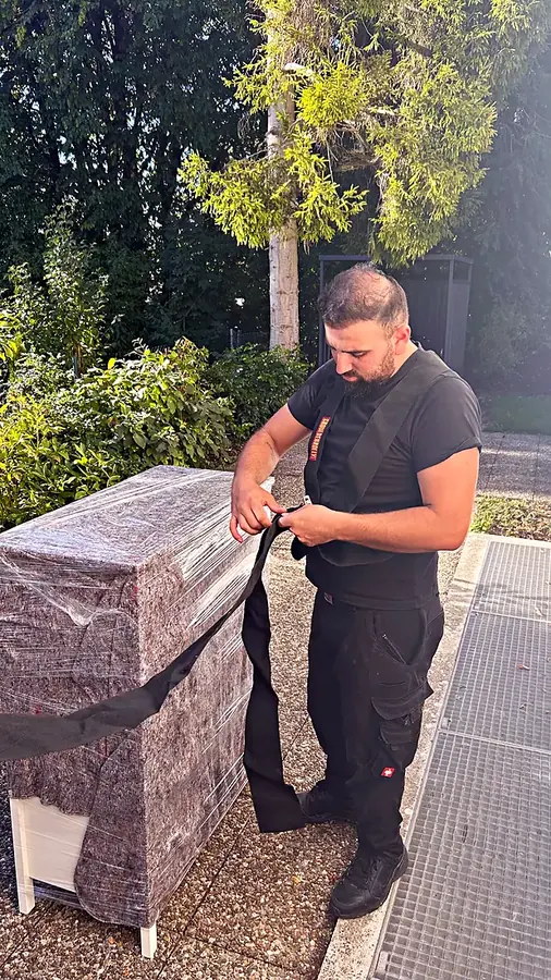 Mitarbeiter wickelt Umzugsdecken um ein Möbelstück