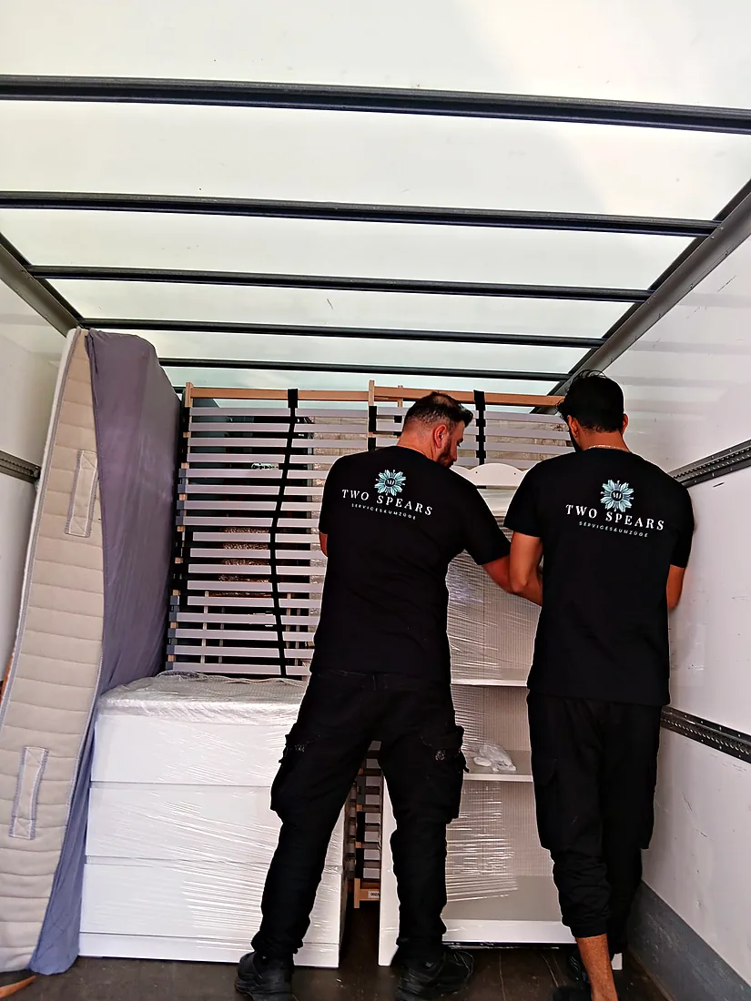 Zwei Two-Spears-Mitarbeiter sichern Lattenroste und Möbel im Umzugswagen
