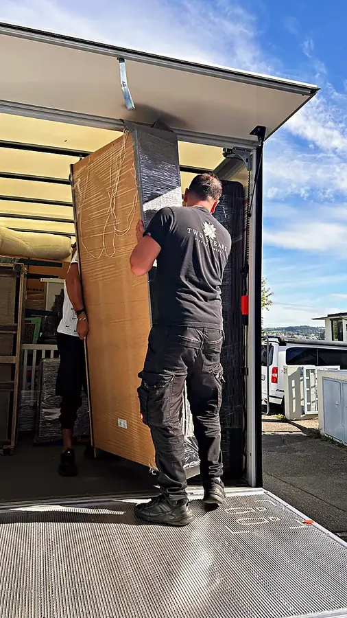 Two-Spears-Mitarbeiter trägt einen großen Schrank in den Umzugswagen