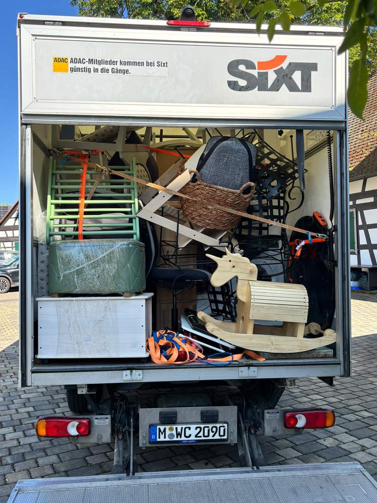 Sorgfältig verladener Umzugswagen mit Möbeln und Kinderspielzeug
